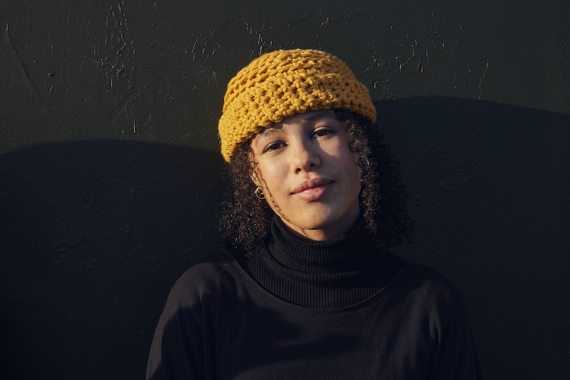 An image of Mel in a yellow crochet hat